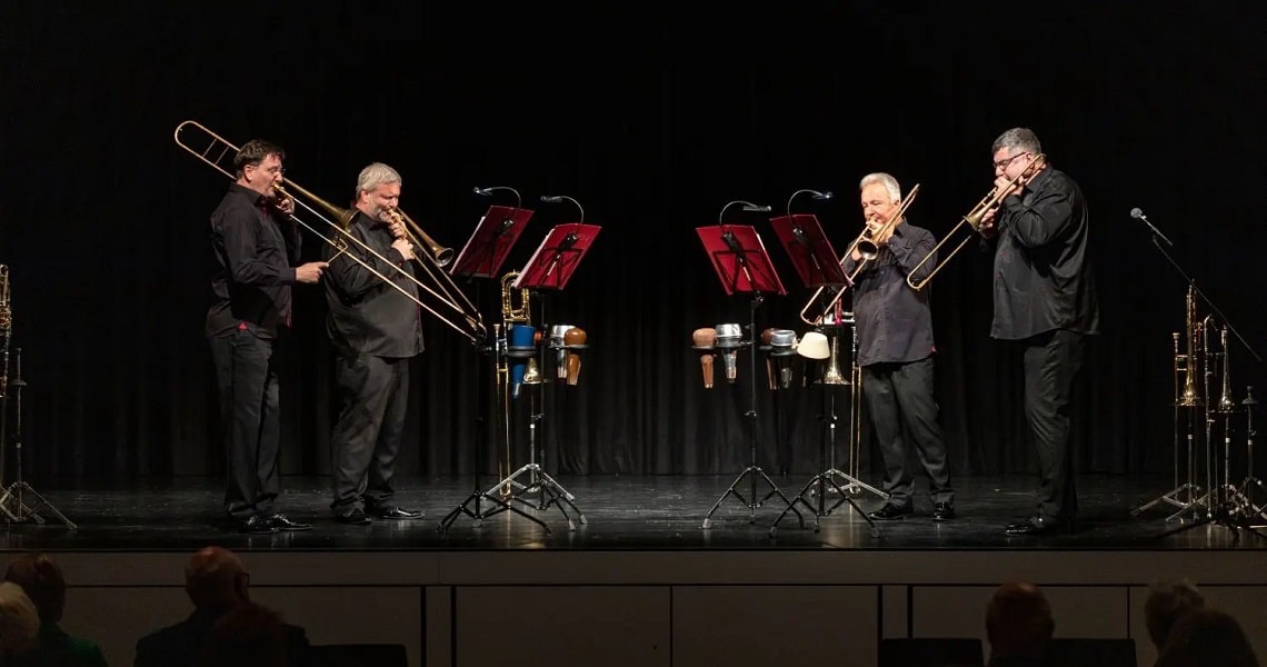 Viel Applaus für Posaunenquartett Opus 4 Das Posaunenquartett Opus 4 während seines Konzerts in der Kulturhalle Süßen. Vier Musiker mit Posaunen stehen nebeneinander auf der Bühne, vor ihnen Notenständer und verschiedene Instrumente.