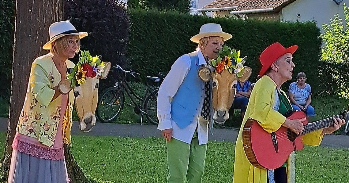 Süßen einmal ganz anders erlebt Drei Darstellerinnen des Ensembles Dein Theater treten beim poetischen Stadtspaziergang in Süßen auf, mit Kuhmasken, bunten Kostümen und Gitarre.