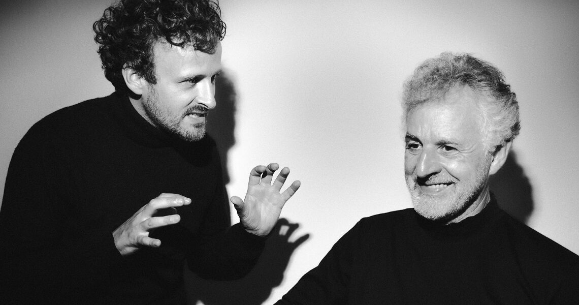 Der jüngere Johannes Mayer (Tenor) gestikuliert lebhaft, während der ältere Hubert Mayer (Klavier) lächelnd zur Seite blickt. Auftritt im Rahmen des Nachmittagstheaters in der Kulturhalle Süßen.