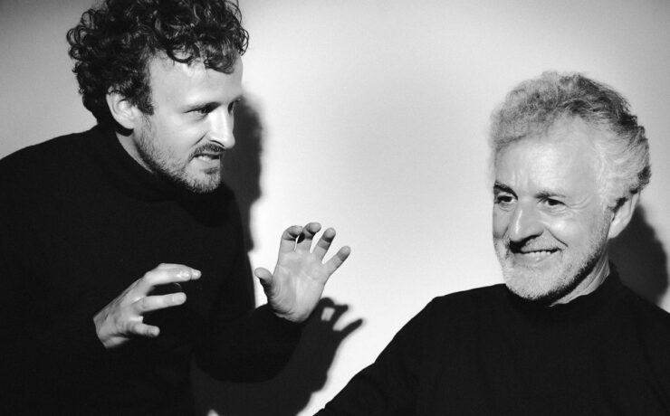 Der jüngere Johannes Mayer (Tenor) gestikuliert lebhaft, während der ältere Hubert Mayer (Klavier) lächelnd zur Seite blickt. Auftritt im Rahmen des Nachmittagstheaters in der Kulturhalle Süßen.