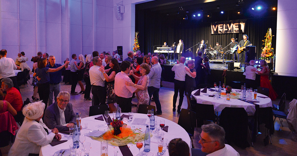 Firmenweihnachtsfeier in Süßen. Festlich geschmückter Saal mit Livemusik der Band „Velvet“, tanzenden Gästen und festlich gedeckten Tischen bei einer Kulturveranstaltung der Stadt Süßen.