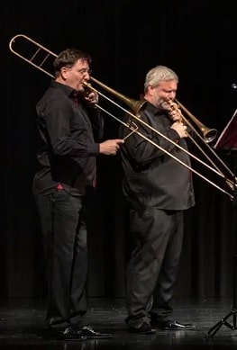 Zwei Mitglieder des Posaunenquartetts Opus 4 spielen auf der Bühne der Kulturhalle Süßen. Beide Musiker stehen nebeneinander, konzentriert beim Spiel auf ihren Posaunen.