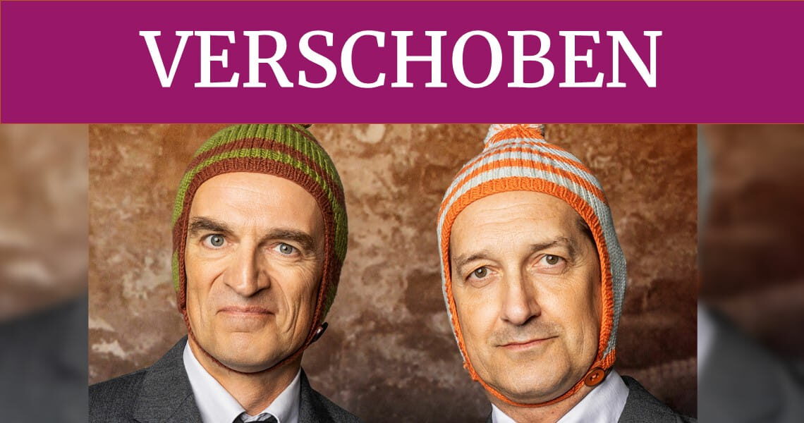 Ulan & Bator mit ihren charakteristischen Wollmützen. Ein violetter Banner mit der Aufschrift „VERSCHOBEN“ weist auf die Verschiebung der Veranstaltung „Überraschungszwei“ in der Kulturhalle Süßen hin.