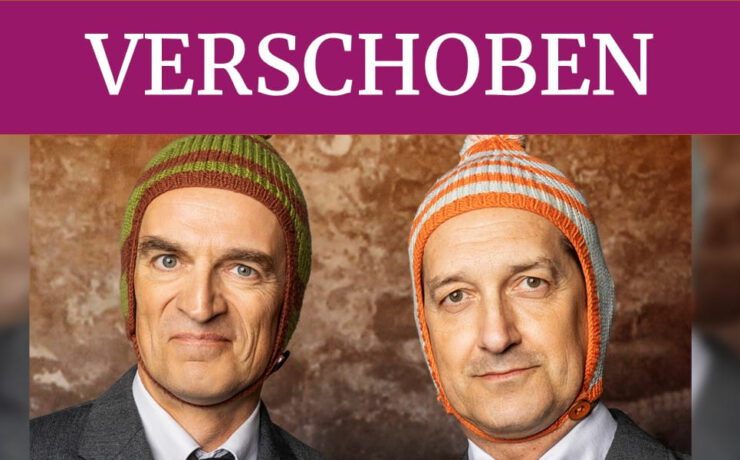 Ulan & Bator mit ihren charakteristischen Wollmützen. Ein violetter Banner mit der Aufschrift „VERSCHOBEN“ weist auf die Verschiebung der Veranstaltung „Überraschungszwei“ in der Kulturhalle Süßen hin.