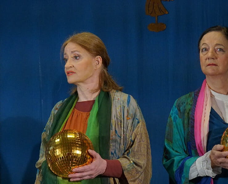 Zwei Frauen auf einer Bühne halten goldene Kugeln in den Händen. Nachmittagstheater: Es wird ein Engel dir gesandt