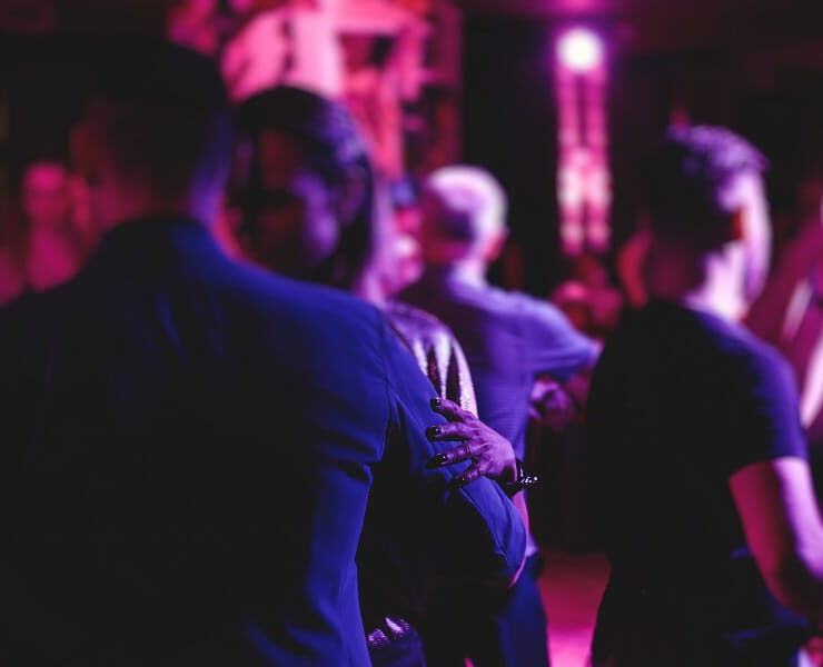 Tanzende Gäste feiern bei stimmungsvoller violett-pinker Beleuchtung auf einer Tanzfläche – passend zur Veranstaltung „Tanz in den Mai“ mit Live-Musik.